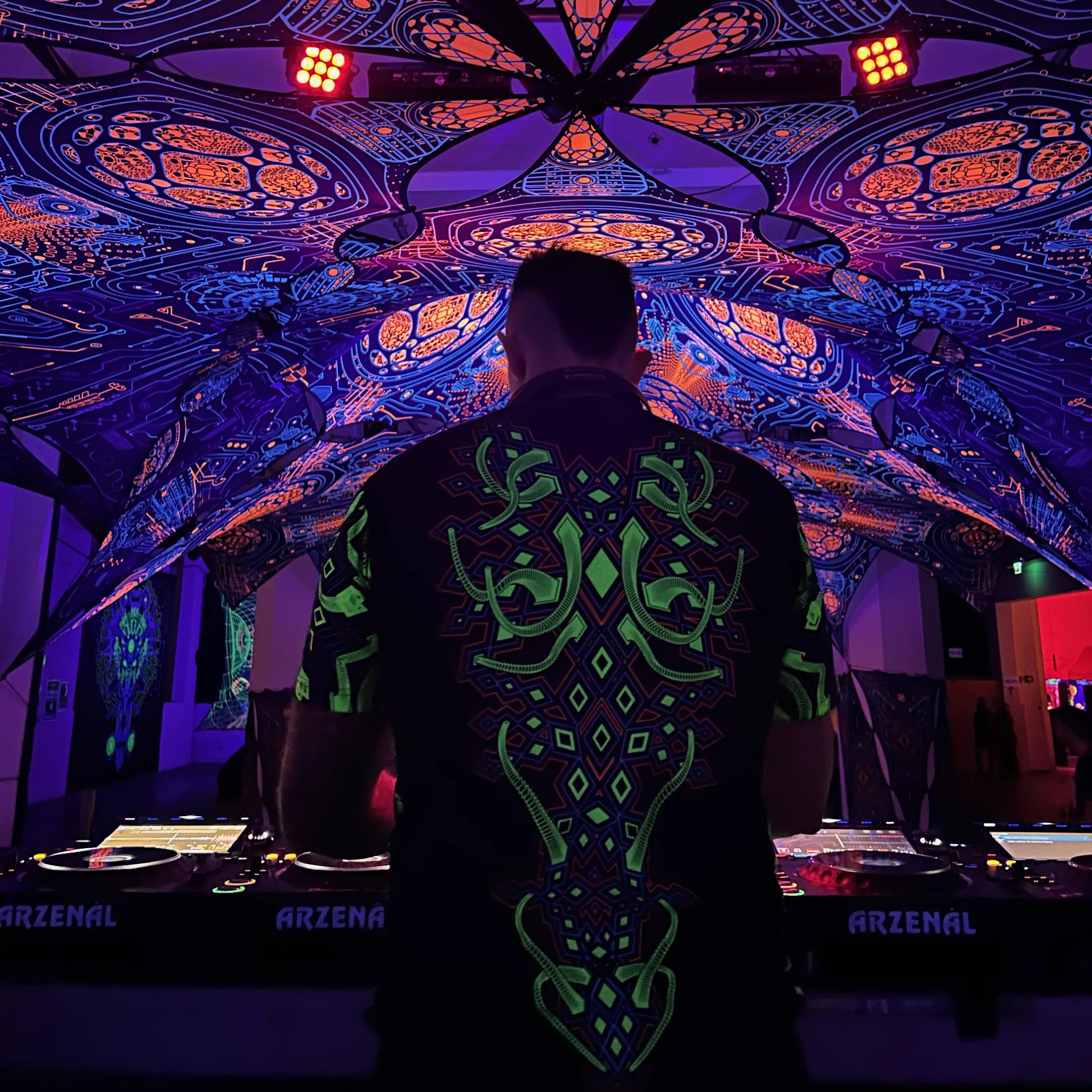DJ wearing a T-shirt with geometric UV-reactive graphics glowing under blacklight