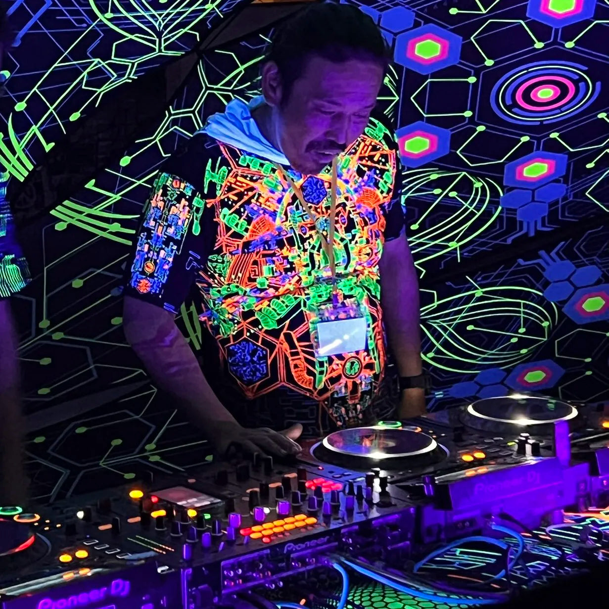 DJ wearing a T-shirt with UV-reactive futuristic print glowing under blacklight front