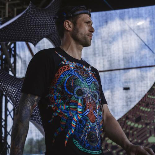 DJ weraing a t-shirt with UV-reactive psychedelic art print, photographed in natural light on stage